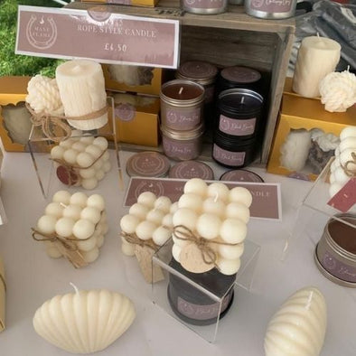 A collection of candles on a table. The products feature shell, bubble, tin and horse head-shaped candles in white and black colours.